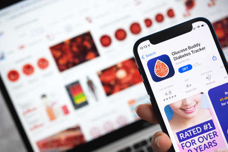 Glucose Buddy Diabetes Tracker app icon. Woman use mobile phone with application tracker photoのeditorial素材