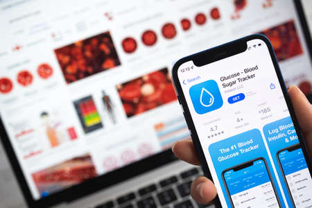 Glucose Blood Sugar Tracker app icon. Woman use mobile phone with application tracker photoのeditorial素材