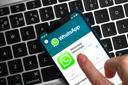 Woman installing Whatsapp app. Hand with mobile phone with application. Messenger and social networking concept photoのeditorial素材