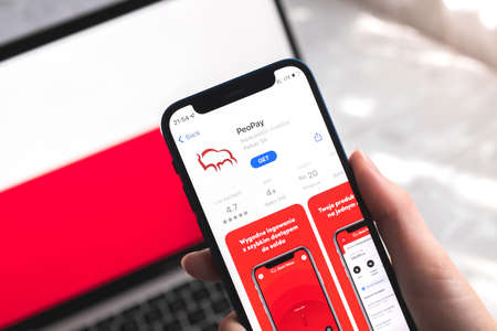 Poltava, Ukraine - April 7, 2022: PeoPay mobile banking app in Poland. Hand with smartphone, on the screen. background with national flag photoのeditorial素材