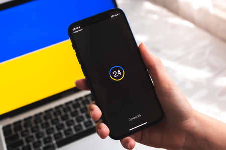 Poltava, Ukraine - April 7, 2022: Privatbank mobile banking app in Ukraine. Hand with smartphone, logo on the screen. background with national flag photoのeditorial素材