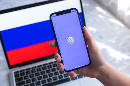 SPB, Russia - April 7, 2022: Gazprombank mobile banking app in Russia. Hand with smartphone, on the screen. background with national flag photoのeditorial素材