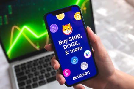 Poltava, Ukraine - April 7, 2022: Kraken crypto currency wallet app. Hand with smartphone, on the screen. stock chart backgroundのeditorial素材
