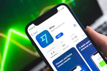 Poltava, Ukraine - April 7, 2022: Wise mobile banking app. Hand with smartphone,  on the screen. stock chart backgroundのeditorial素材