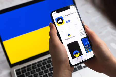 Poltava, Ukraine - April 8, 2022: Air Raid Siren app for mobile phone. Smartphone with modern air alarm application for Ukraine. Flag on background photoのeditorial素材