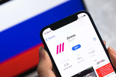 Poltava, Ukraine - April 8, 2022: TV Rain app, Russia flag background. Blocked news application in Russian Federation, mobile phone with icon close-up view photoのeditorial素材