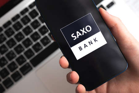 Poltava, Ukraine - April 9, 2022: Saxo Bank app. Trader and broker application. mobile phone in hand close-up viewのeditorial素材