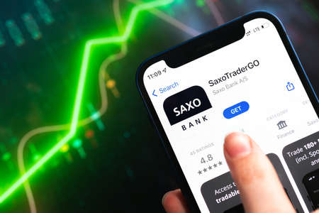 Poltava, Ukraine - April 9, 2022: Saxo Trader Go app and Saxo Bank application icon on the mobile phone screen close-up viewのeditorial素材
