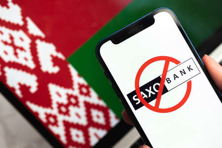 SPB, Russia - April 9, 2022: Saxo Trader and Bank in Belarus. Blocked and banned application and company in Belarus, flag backgroundのeditorial素材
