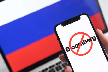 SPB, Russia - April 8, 2022: Bloomberg in Russia. Blocked and banned service, EU sanctions. Mobile phone with , russian flag background photoのeditorial素材