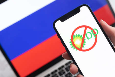 SPB, Russia - April 8, 2022: BP British Oil And Gas company in Russia. Blocked and banned service, EU sanctions. Mobile phone with , russian flag background photoのeditorial素材