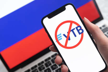 SPB, Russia - April 8, 2022: VTB bank and sanctions. Blocked Russian bank, and ban symbol on mobile phone screen and flag backgroundのeditorial素材