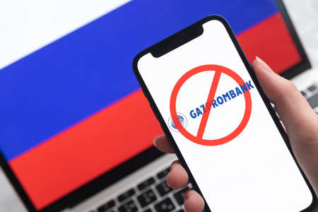 SPB, Russia - April 8, 2022: Gazprombank and sanctions. Blocked Russian bank, and ban symbol on mobile phone screen and flag backgroundのeditorial素材
