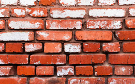 Old red brick wall with weathered white paint, high detailed texture backgroundの写真素材