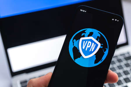 VPN in Estonia. Secure and safe internet concept. privacy. Hand with mobile phone and VPN application. Flag and laptop on the background photoの写真素材