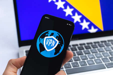 VPN in Bosnia and Herzegovina. Secure and safe internet concept. privacy. Hand with mobile phone and VPN application. Flag and laptop on the background photoの写真素材