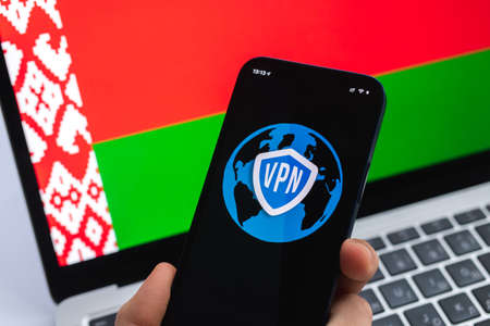 VPN in Belarus. Secure and safe internet concept. privacy. Hand with mobile phone and VPN application. Flag and laptop on the background photoの写真素材