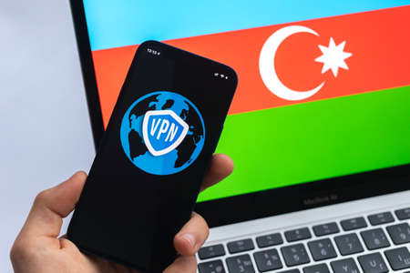 VPN in Azerbaijan. Secure and safe internet concept. privacy. Hand with mobile phone and VPN application. Flag and laptop on the background photoの写真素材