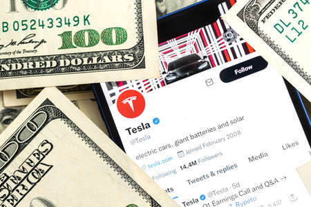 Tesla car company stock market background. Tesla on Twitter and dollar money close-up view photoのeditorial素材