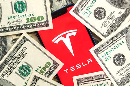 Tesla car company stock market background. Tesla on Twitter and dollar money close-up view photoのeditorial素材