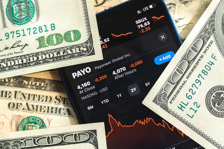 Poltava, Ukraine - April 28, 2022: Payoneer stock trade market background, finance and business concept with dollar money banknotes closeupのeditorial素材