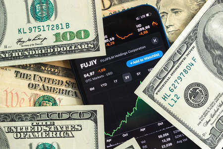Poltava, Ukraine - April 28, 2022: Fujifilm stock trade market background, finance and business concept with dollar money banknotes closeupのeditorial素材