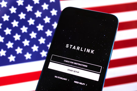 Poltava, Ukraine - April 28, 2022: Starlink app against American flag, USA background. Satellite internet modern technology provided by Elon Musk photoのeditorial素材