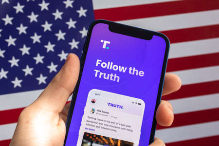 Poltava, Ukraine - April 28, 2022: Truth Social displayed on a smartphone against USA flag background. Social media app by Trump Media photoのeditorial素材