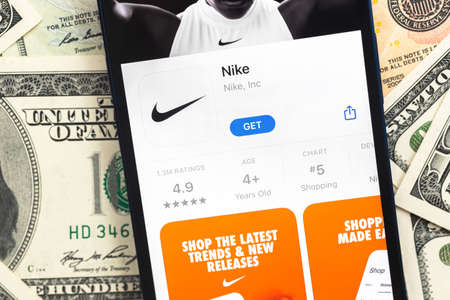 Poltava, Ukraine - April 28, 2022: Nike fashion shopping app on mobile phone screen. Business background with dollar money banknotesのeditorial素材