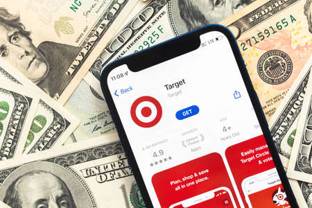 Poltava, Ukraine - April 28, 2022: Target shopping app on mobile phone screen. Business background with dollar money banknotesのeditorial素材