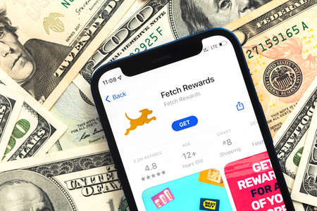 Poltava, Ukraine - April 28, 2022: Fetch Rewards app on mobile phone screen. Business background with dollar money banknotesのeditorial素材