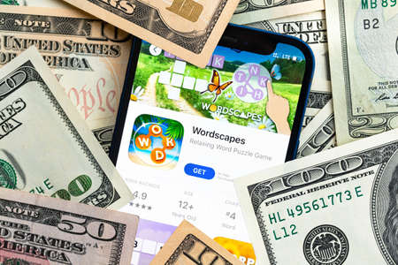 Wordscapes mobile game app. Money background. Concept, company making money with popular mobile phone gamesのeditorial素材