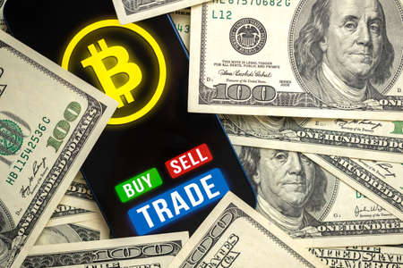 Bitcoin trading concept. Mobile phone application for cryptocurrency. Buy and sell new virtual money. Money dollars background, financial investmentの写真素材