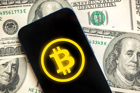 Bitcoin logo, mobile phone application for cryptocurrency. Buy and sell new virtual money. Money dollars background, financial investmentの写真素材