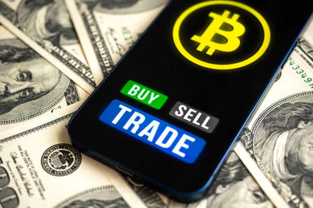 Bitcoin trading concept. Mobile phone application for cryptocurrency. Buy and sell new virtual money. Money dollars background, financial investmentの写真素材