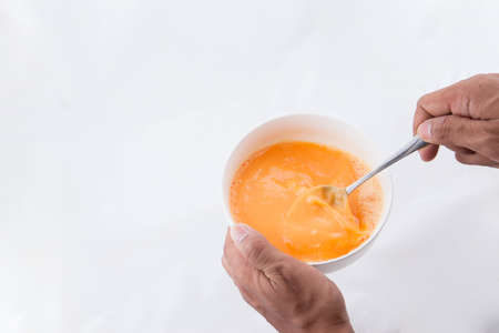 preparing omelet .Cooking of eggs in White Ceramic Bowl. Healthy breakfast protein ingredient. Scrambled eggs preparation. Beating egg with spoonの写真素材