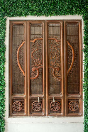 Brown Chinese Art Window On a wall of grass with grass.の写真素材