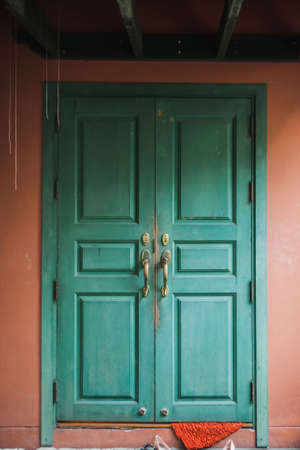 Green door on orange wall .Colorful Orange Facade with Blue Greenish Doorの写真素材
