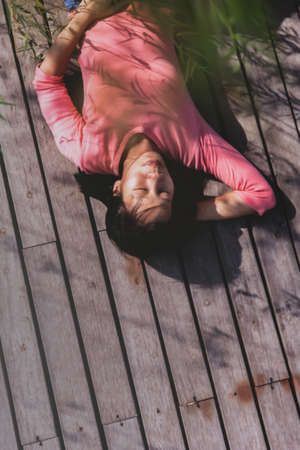 Top view of attractive Thai girls while lying on the wooden floor.Warm with the setting sunの写真素材