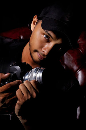 Attractive male photographer, close-up, head and face,black background and brown sofa ,