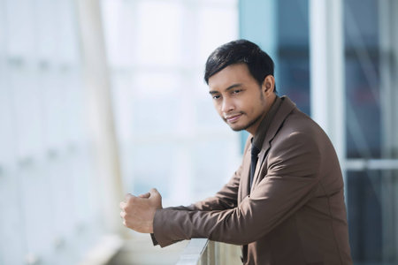 Businessman in brown suit. Thinking. Company background. Glass building.Take a close-up of the head...