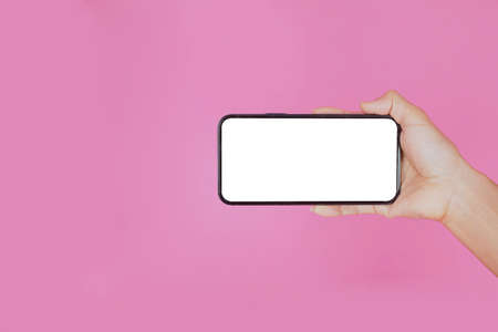 woman hand holding a mobile phone isolated on pink background.view down, press downの写真素材