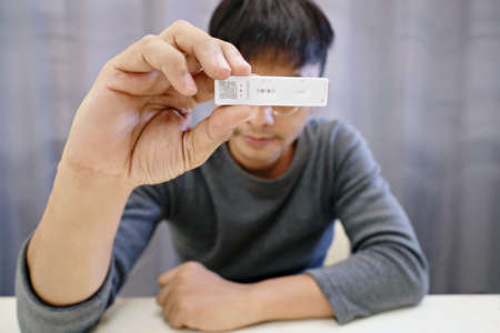 Man shows results of coronavirus test with covid-19 self-test (rapid antigen test).The test result came out positive. There is a corona virus in the body.Select a specific focusの写真素材