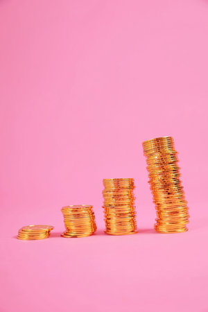 gold coin image on pink scene.gold coin height photo gradient from low to high.Financial communication and investment risk managementの写真素材