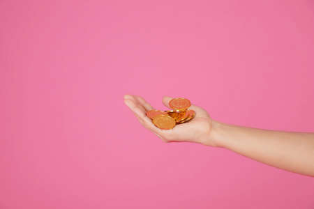 Hand holding a lot of gold coins on the isolate pink scene,The concept of obtaining high-value itemsの写真素材