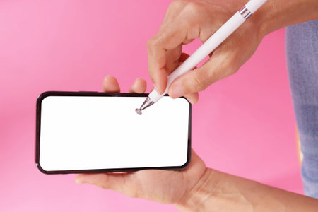 hand holding phone with a pen for a smartphone.on the pink scene isolate.empty space for text