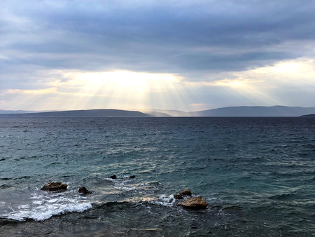 Spectacular light rays (god rays) hitting the sea surface during a cloudy day, coastal landscape...