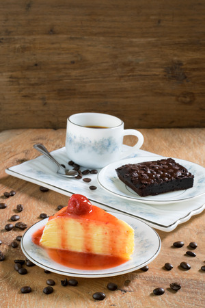 Strawberry crepe cake, brownie and a cup of coffee on wooden backgroundの写真素材