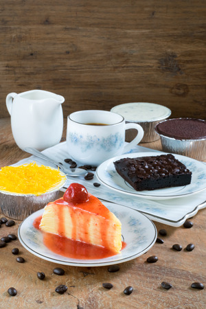 strawberry crepe cake, vanilla cake, soft chocolate cake, brownie and a cup of coffee on wooden backgroundの写真素材