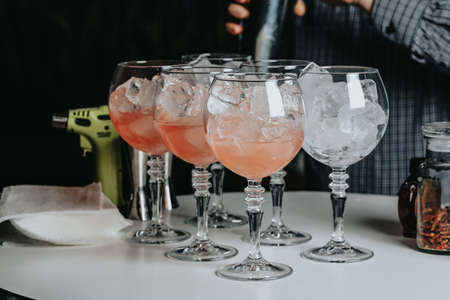 Cocktails with champagne in wine glasses on the bar table in the pub or restaurant with the bartender.の写真素材